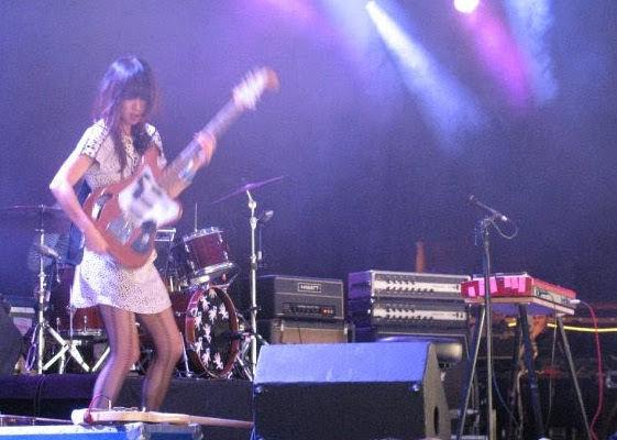 Femme jouant de la guitare sur une scène.